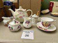 Photo showing set of English porcelain tea items with floral designs on a table.