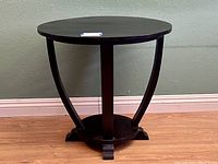 Front view of the round side table showing the curve of the supports and base details.