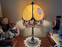 Full view of the lamp lit, showing yellow stained glass shade and surrounding room objects.