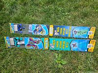 Two kites in packaging laid on grass, showing the full length of the packaged kites and branding.