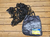 Cargo net laid out on wood surface with black carrying/storage bag