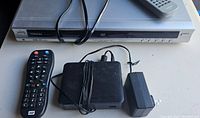 Toshiba DVD player with remote and power cable, WD media box with power adapter and remote shown from top view.
