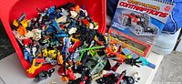 Bin filled with assorted Lego Bionicle and Star Wars figures, loose parts and a Lego book
