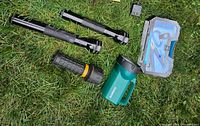 Two large black Maglite flashlights and a black Garrity flashlight with yellow trim, green Ozark Trail handheld spotlight, and blue plastic tool kit case on grass