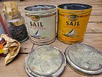 Photo of two vintage Sail tobacco tins and glass jar with nails and paper wrappings.