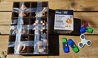 Wooden 3D puzzle pieces arranged in a box with a puzzle box labeled 31 pc 3D puzzle 6+ and four fidget spinners of different colors beside it.