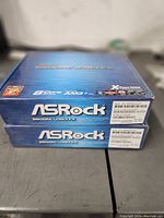 Two ASRock 960GM/U3S3 FX motherboard boxes stacked showing front and side panel.