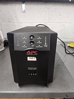 Front view of APC Smart-UPS 1500 unit showing control panel, LED indicators, and brand labels