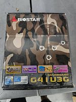 Box of Biostar G41U3G Mainboard showing camouflage design with bullet holes and product features
