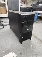 Front angled view of black Bose subwoofer with ventilation grills and Bose logo plate on front.