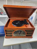 Top view of Crosley wooden cabinet record player with hinged lid open showing turntable and tonearm.