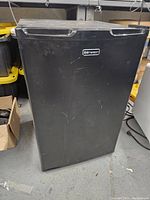 Front view of the black Emerson mini fridge with visible brand logo and minor surface scratches.