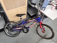 Side view of entire bike showing blue and red color scheme, Huffy branding, tires needing air.