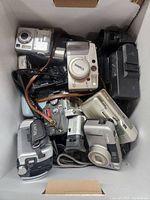 Box containing multiple old cameras, including Canon and Sony models in various conditions.