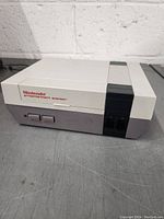 Front view of the Nintendo Entertainment System showing power/reset buttons, cartridge slot, and controller ports.