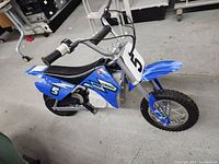 Side profile of the blue Razor MX350 mini bike showing body, seat, tires, and handlebars.