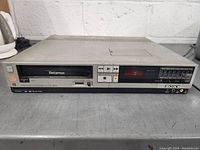 Front view of the Sony Betamax SL-2300 video cassette recorder showing the Betamax cassette slot, control buttons, numeric keypad, and digital display on a silver/black metal unit.