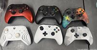 Front view of six Xbox wireless controllers showing various colors and designs