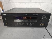 Front view showing Yamaha branding, display powered on with Sci-Fi input selected, knobs, and input ports.