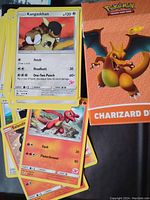 Close-up of Pokémon trading cards featuring Kangaskhan and Salandit with visible attack details