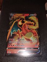 Photo shows a single Charizard V Pokemon card with full art holo finish. Card features 220 HP, Incinerate and Heat Blast attacks.