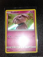 Front view of Snubull holo Pokémon card showing artwork, holo shine, and card details.