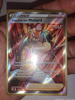 Full view of the Full Art Trainer Single Strike Mustard holographic foil Pokémon card held by a hand, showing artwork and game text clearly.