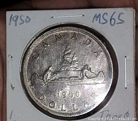 Front detail of 1950 Canada silver dollar showing voyageur canoe and deer design, graded MS65