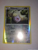 Photo of a holographic Wishmer Pokémon card with gold border and holo foil background, showing character and moves.