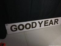 Full view of the cast iron letters spelling GOODYEAR mounted on a white melamine board, showing the entire length and size.