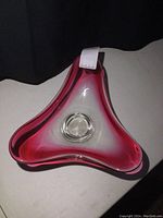 Triangular art glass bowl with deep pink-red gradient fading to clear glass, smooth and glossy finish, curved edges, viewed from top.
