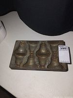 Top view of old metal chocolate mold with eight bell-shaped cavities.