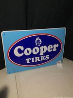 Front view of Cooper Tires sign showing full design on light blue background