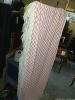 Full view of the bedspread showing the pink diamond lattice pattern and white fringe.