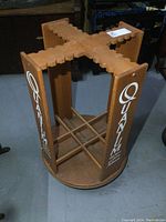 Overall front view of the wooden rotisserie fishing pole display rack with Quantum branding featuring the round base and vertical panels with the logo.