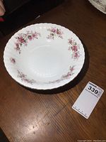 Top view showing floral lavender rose pattern around the inside rim and scalloped edge of the white serving bowl.