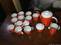 Full tea set including teapot, sugar bowl, creamer, and 12 cups arranged on a wooden table.