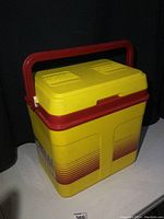 Front and side view showing yellow cooler with red handle and Shell Formula branding.