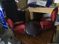 Pair of two solid wood children's chairs with red velour upholstery and solid wood oval coffee table arranged together