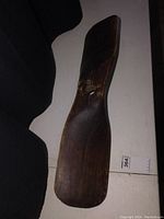 Full view of a dark solid wood propeller with visible aged wear and a central mounting hole.