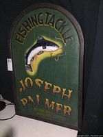 Front view of painted wood fishing tackle sign showing full text and fish illustration.