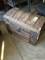 Front and side view of an antique wood and metal humpback trunk showing patina and aged wear.
