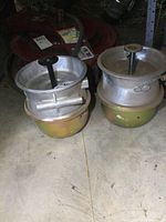 Two new heavy truck brake chambers set side by side on a floor surface with storage shelving in background.