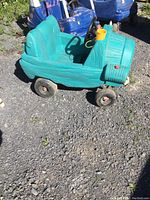 Side view of green children's resin push car showing bucket seat and body design