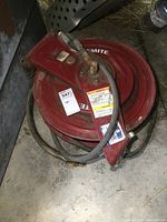Top view of red round steel airline reel with hose showing label and wear.