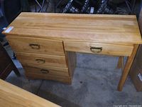 Front angled view of the solid maple desk showing the drawer fronts with brass pull handles and smooth wood top.