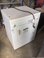 White Kenmore electric dryer with power cord on top showing overall condition and door with handle.