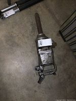 Full length image of a heavy duty 1-inch pneumatic impact driver on concrete floor, showing overall length and condition.