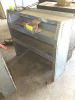 Front and side view of steel heavy duty garage shelf with contents on middle shelf.