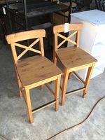 Two IKEA solid wood bar height chairs paired together, showing front, side and top views. Light natural wood finish with minor signs of wear.